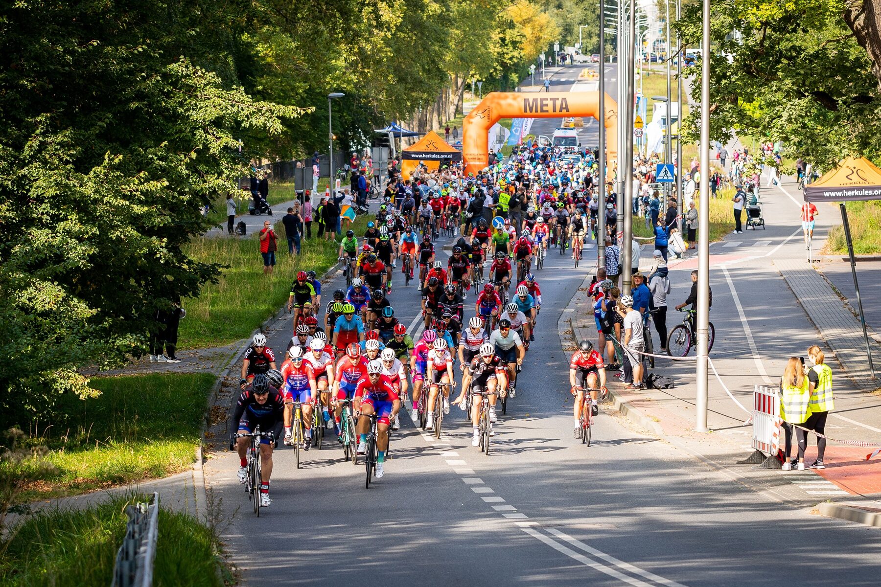 Départ d'une course à pied en extérieur, nombreux participants, ciel dégagé, public le long du parcours