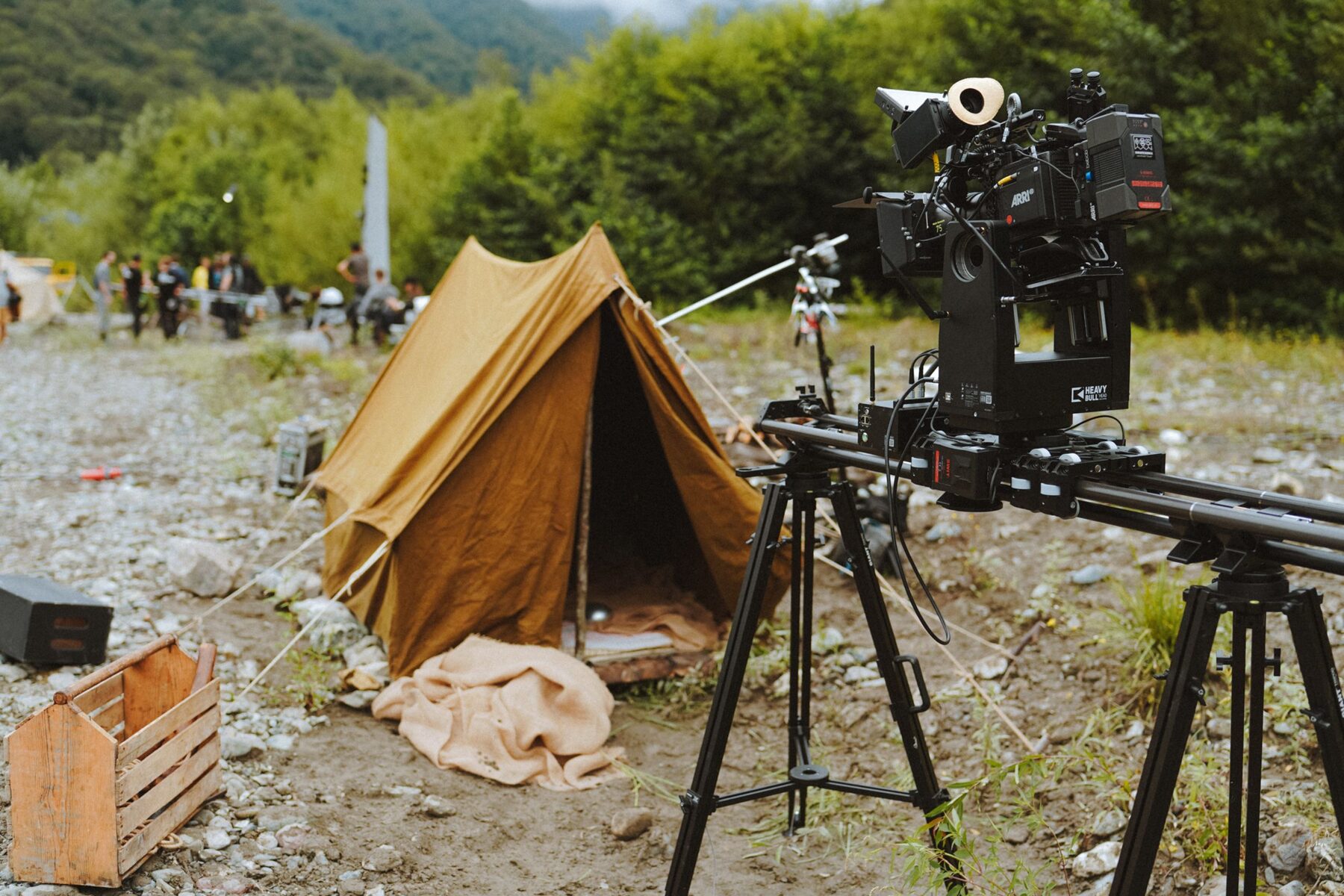 Équipe de production vidéo en extérieur, caméra sur trépied, lumière naturelle de golden hour, décor paysager